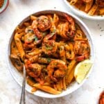 Creamy Cajun Shrimp Pasta in a white bowl with a lemon wedge garnish