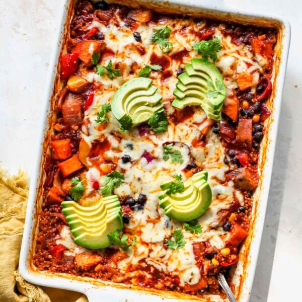 Quinoa Enchilada Casserole in a white pan topped with avocado slices