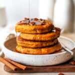 Stack of pumpkin protein pancakes being drizzled with syrup