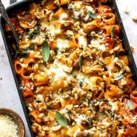 Rigatoni in a baking pan with tomato sauce topped with cheese