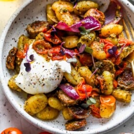 Pesto gnocchi with tomatoes and burrata in a white bowl to showcase summer pasta recipes.