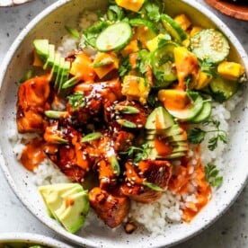 Salmon sushi bowl with cucumber-mango salsa and aioli in a white bowl