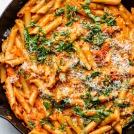 One pan creamy tomato pasta in a cast iron skillet topped with basil and parmesan.