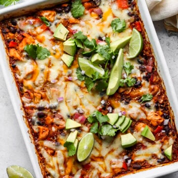 Chicken Enchilada Bake styled in a white baking dish topped with avocado and cilantro