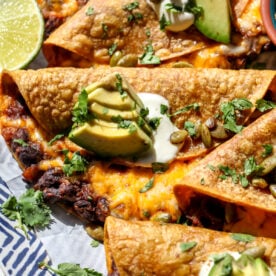 Crispy chipotle black bean pumpkin tacos arranged on a platter showing gooey insides.