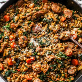 Tuscan sausage and lentils in a cast iron skillet topped with grated cheese.