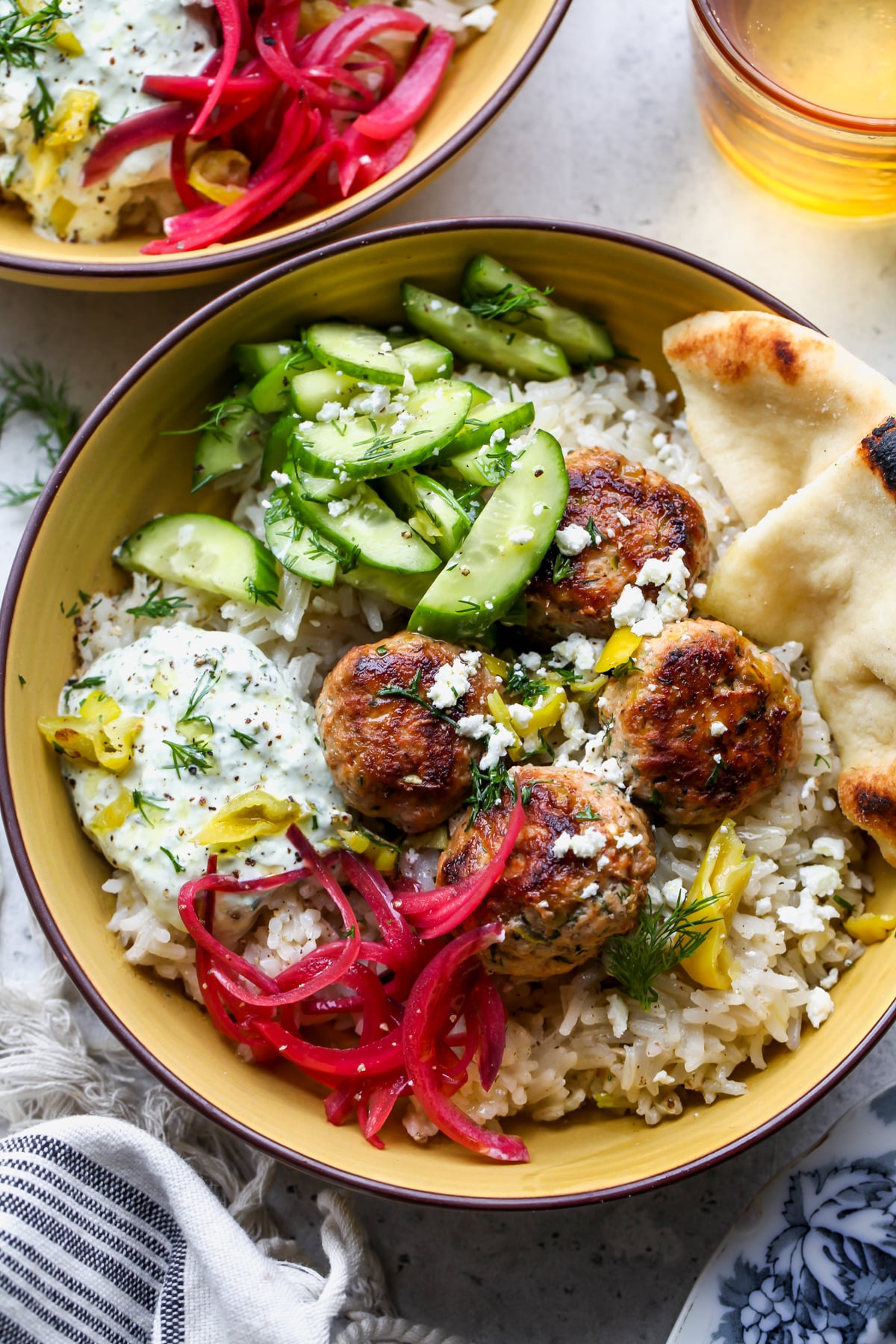 Turkey Meatballs, rice, cucumbers, pickled onion, and pita assembled in a yellow serving bowl.
