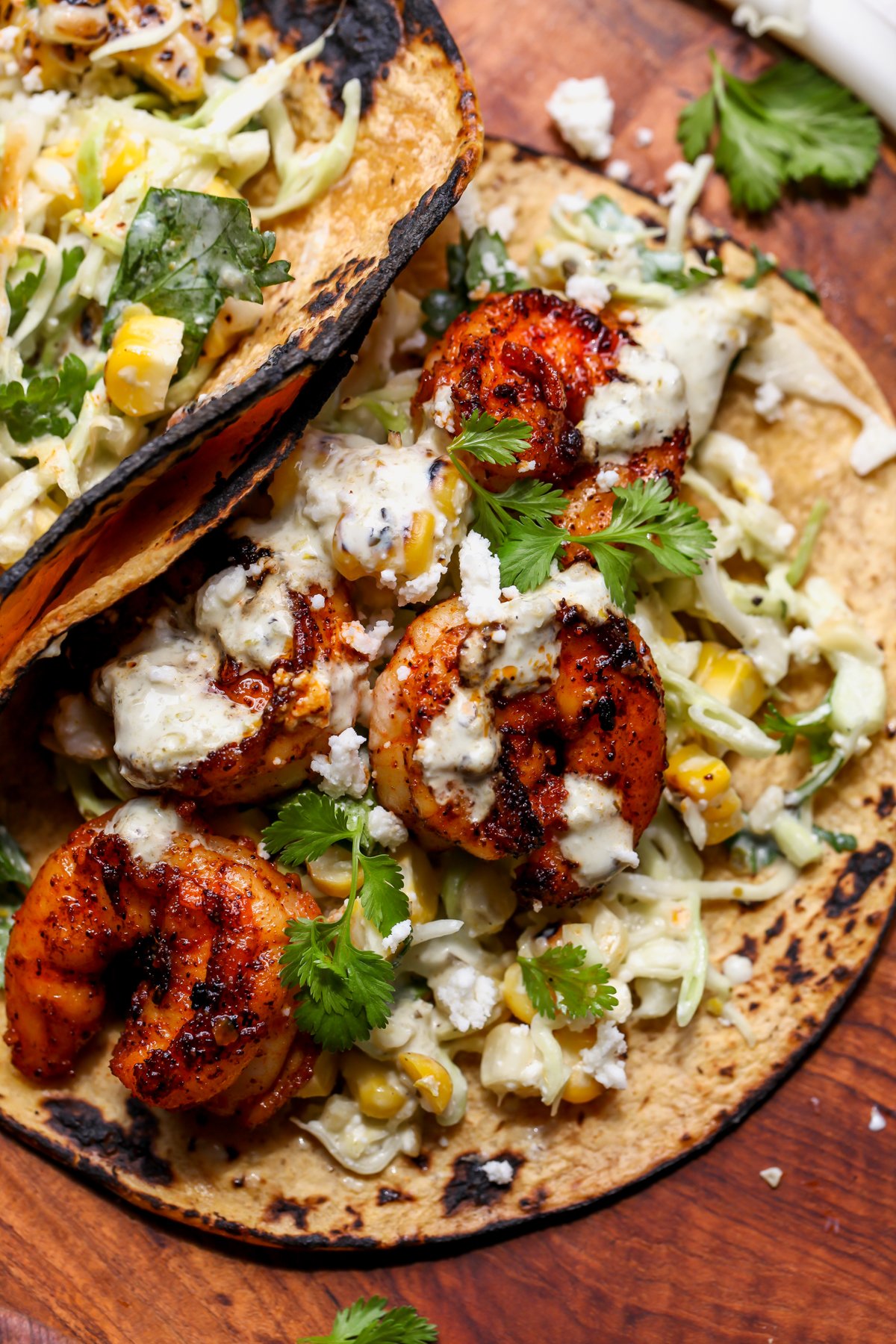 Easy shrimp taco topped with cilantro, crumbled cheese, and creamy salsa verde styled on a wooden serving platter.