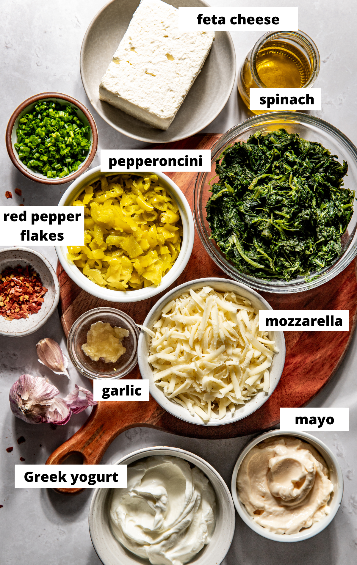 Recipe ingredients arranged on a wooden serving board in separate bowls with labels.