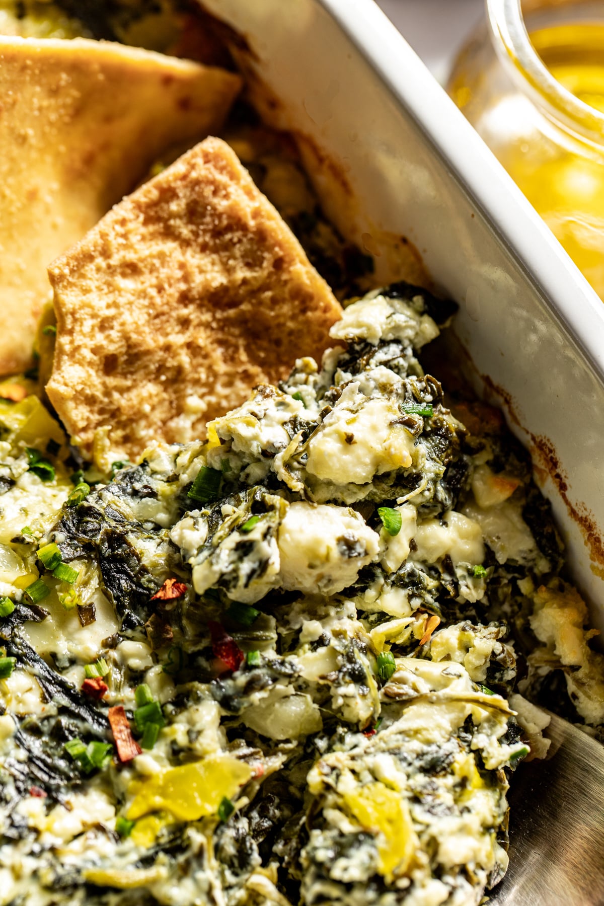 Pita chips scooping up a portion of baked feta dip.