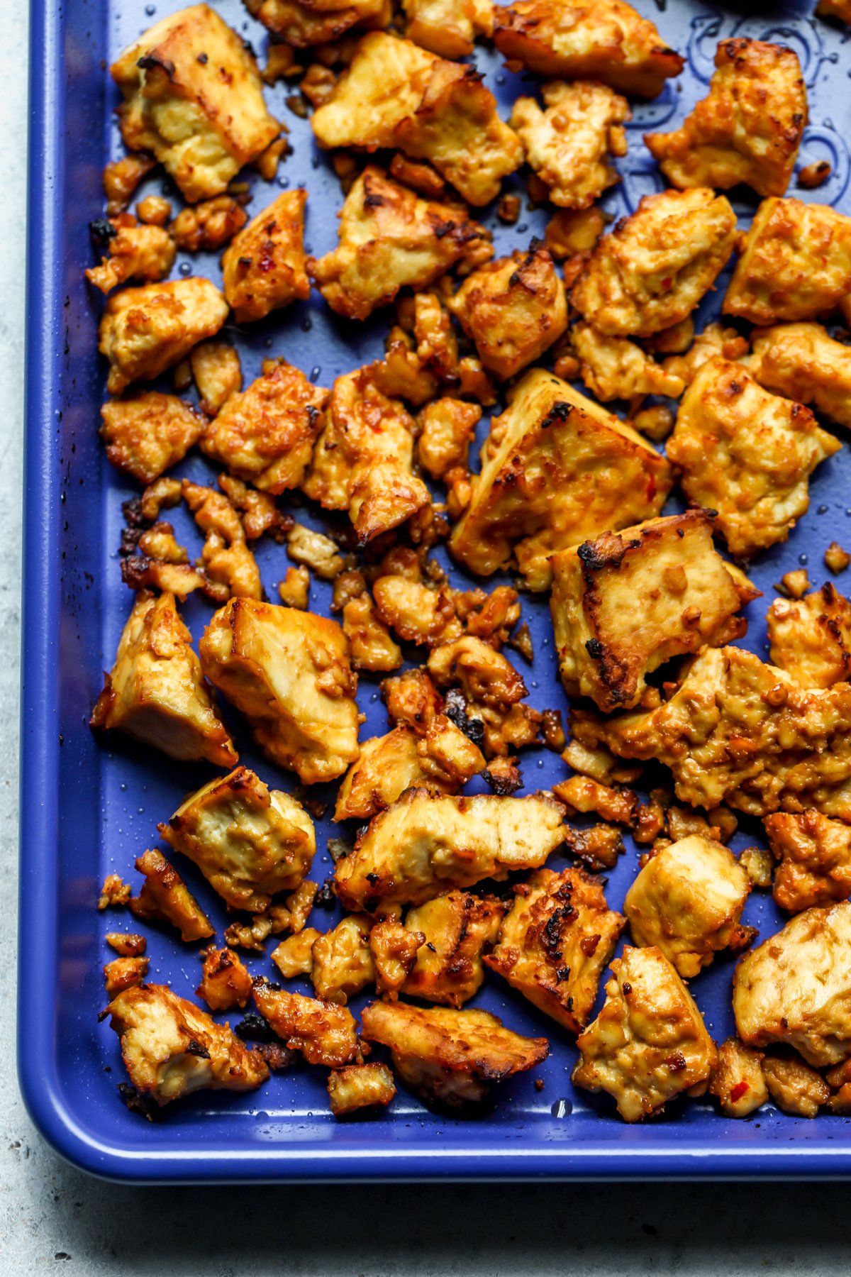 A blue baking sheet with crispy sweet chili tofu after baking.