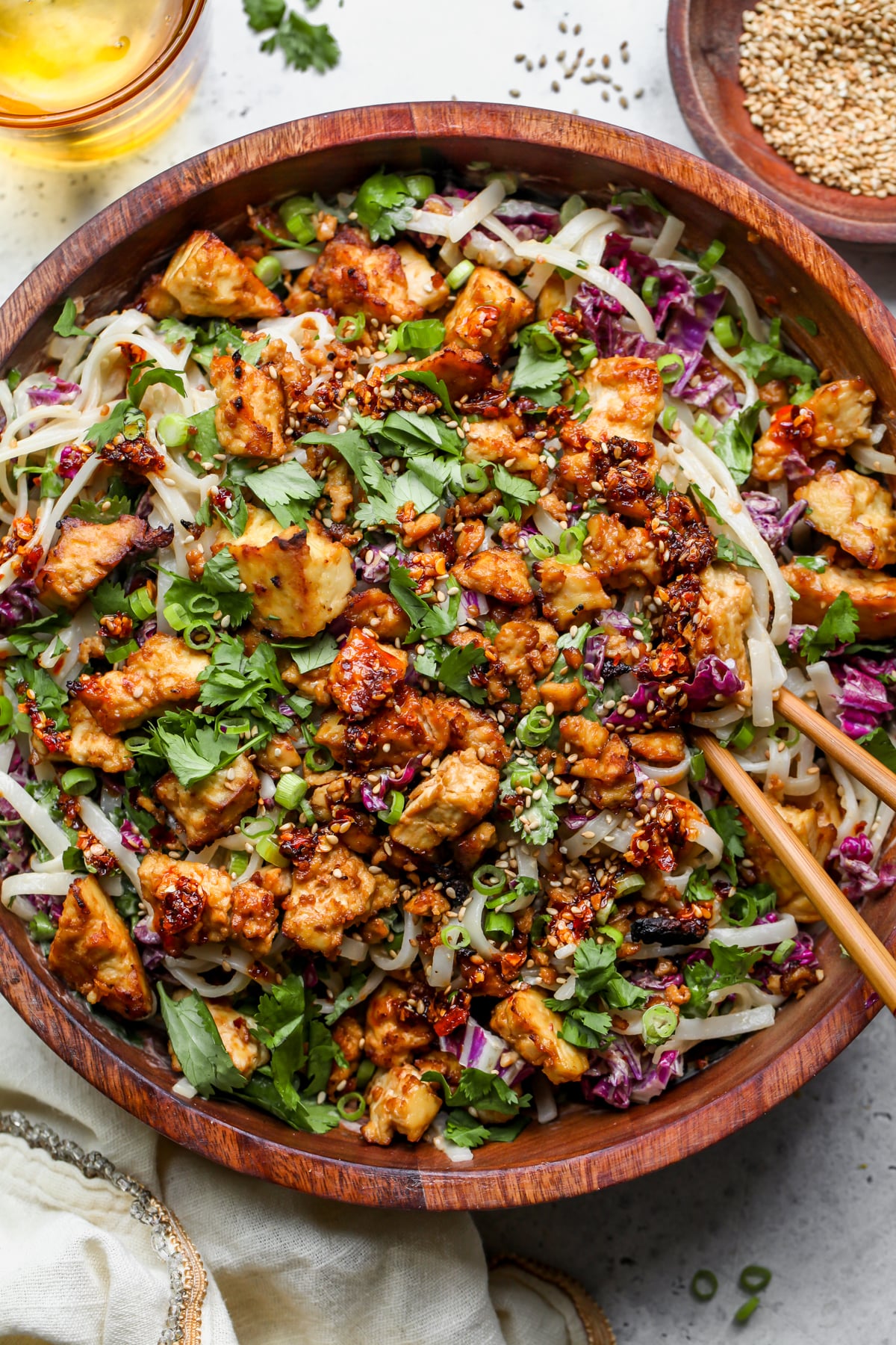 Sesame rice noodle salad styled in a wooden serving bowl with a set of chopsticks resting on the right side.