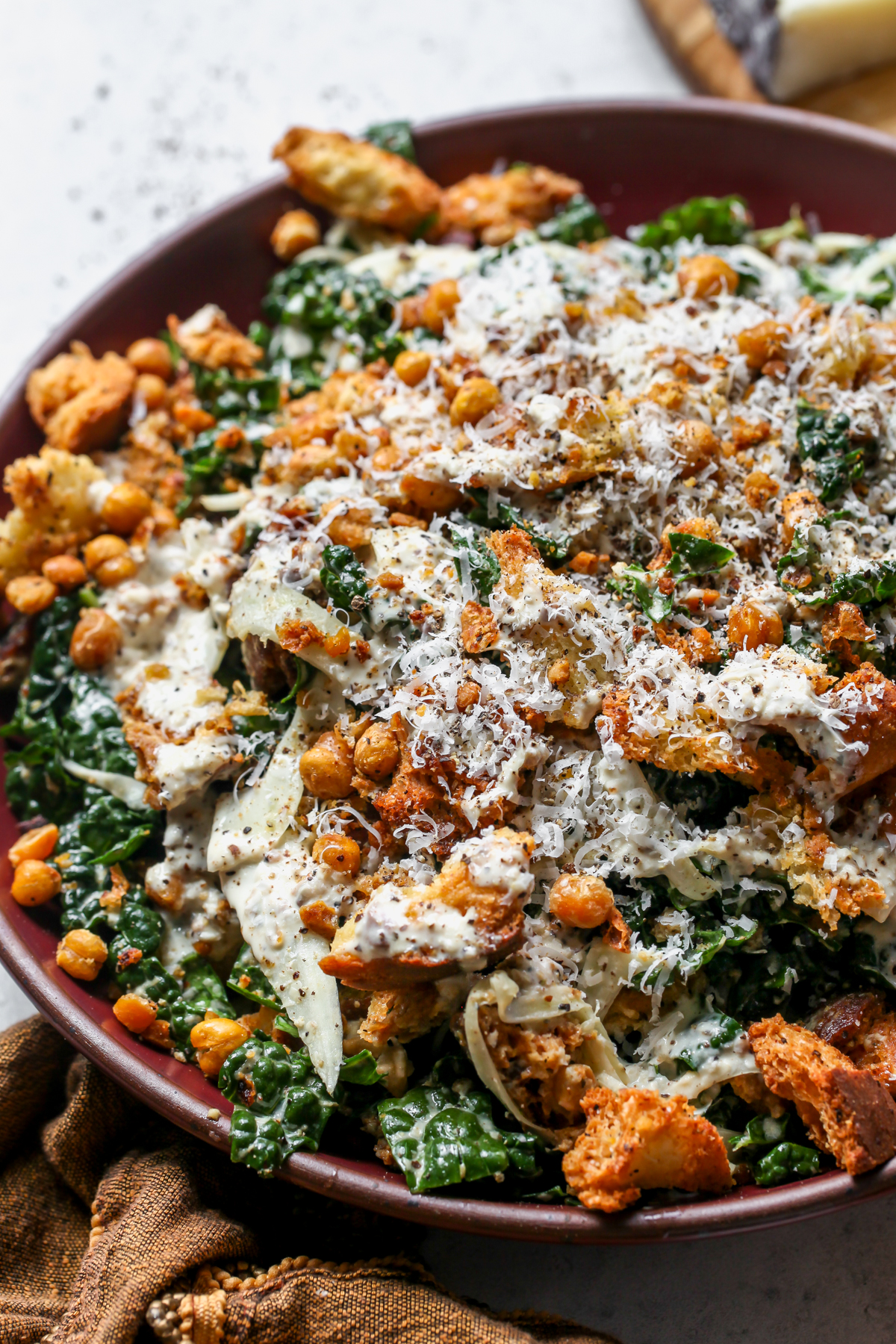 Cacio e Pepe Kale and Fennel Caesar Salad topped with chickpea-ciabatta crumble in a large serving bowl.