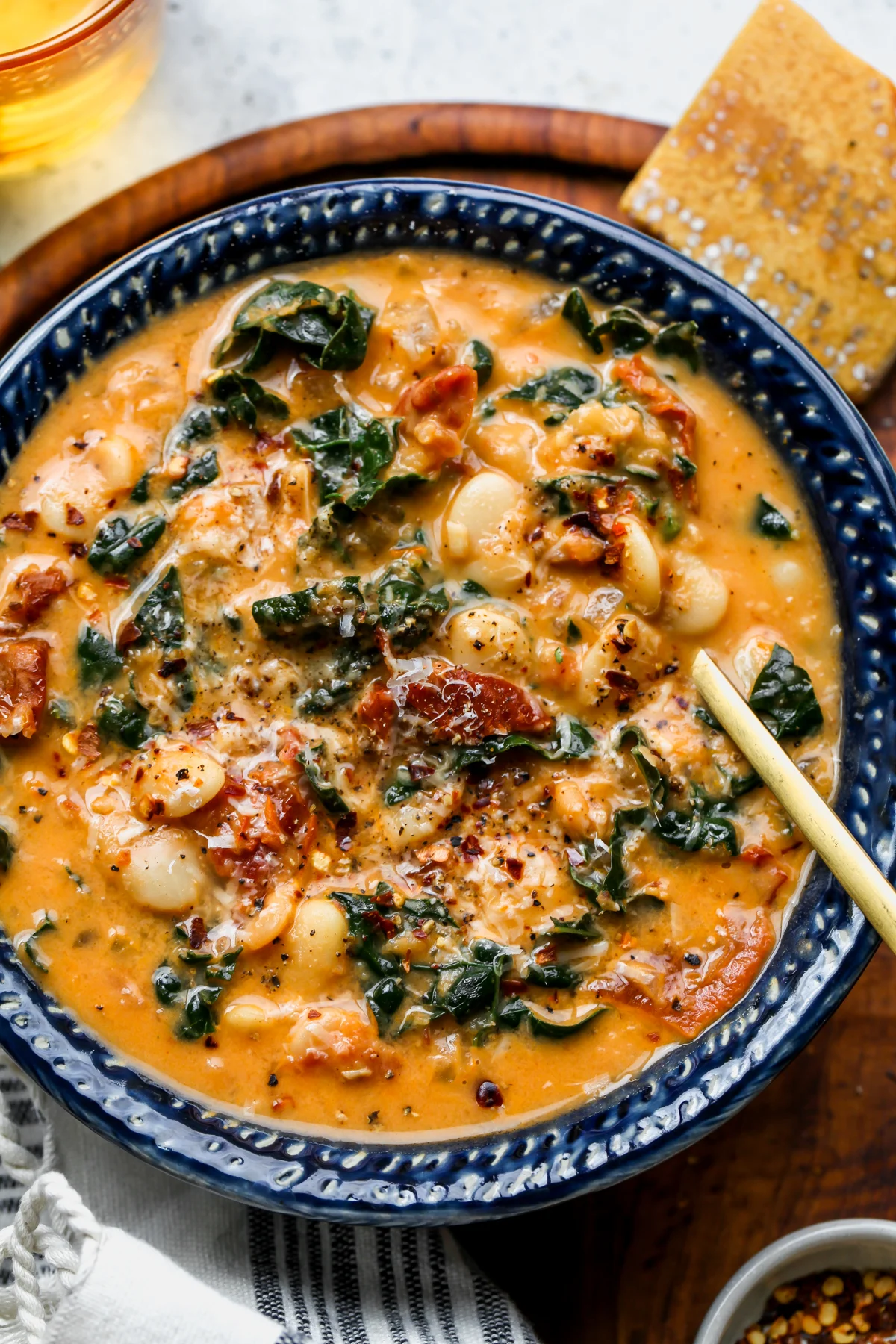 A golden spoon resting on the right side of a blue bowl filled with butter bean soup.