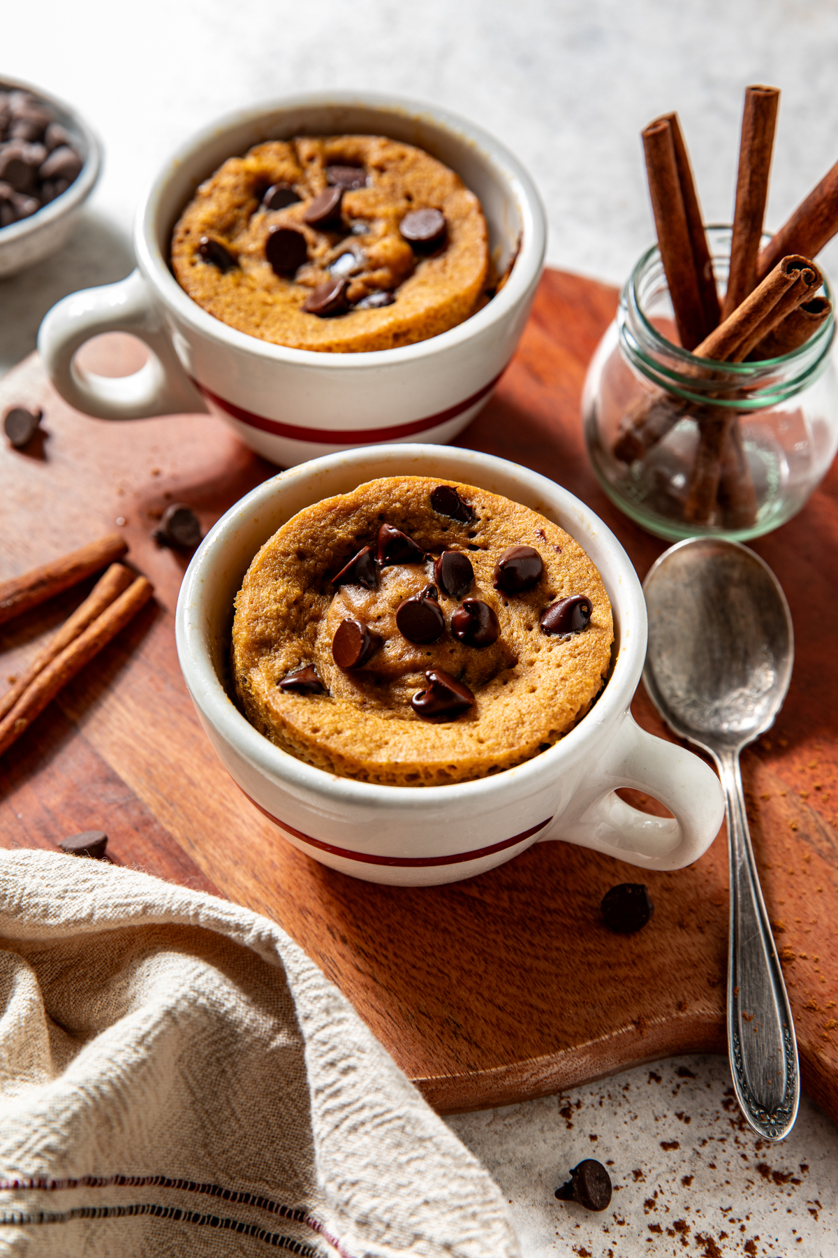 Two pumpkin mug cakes shown on a wooden surface after being microwaved.