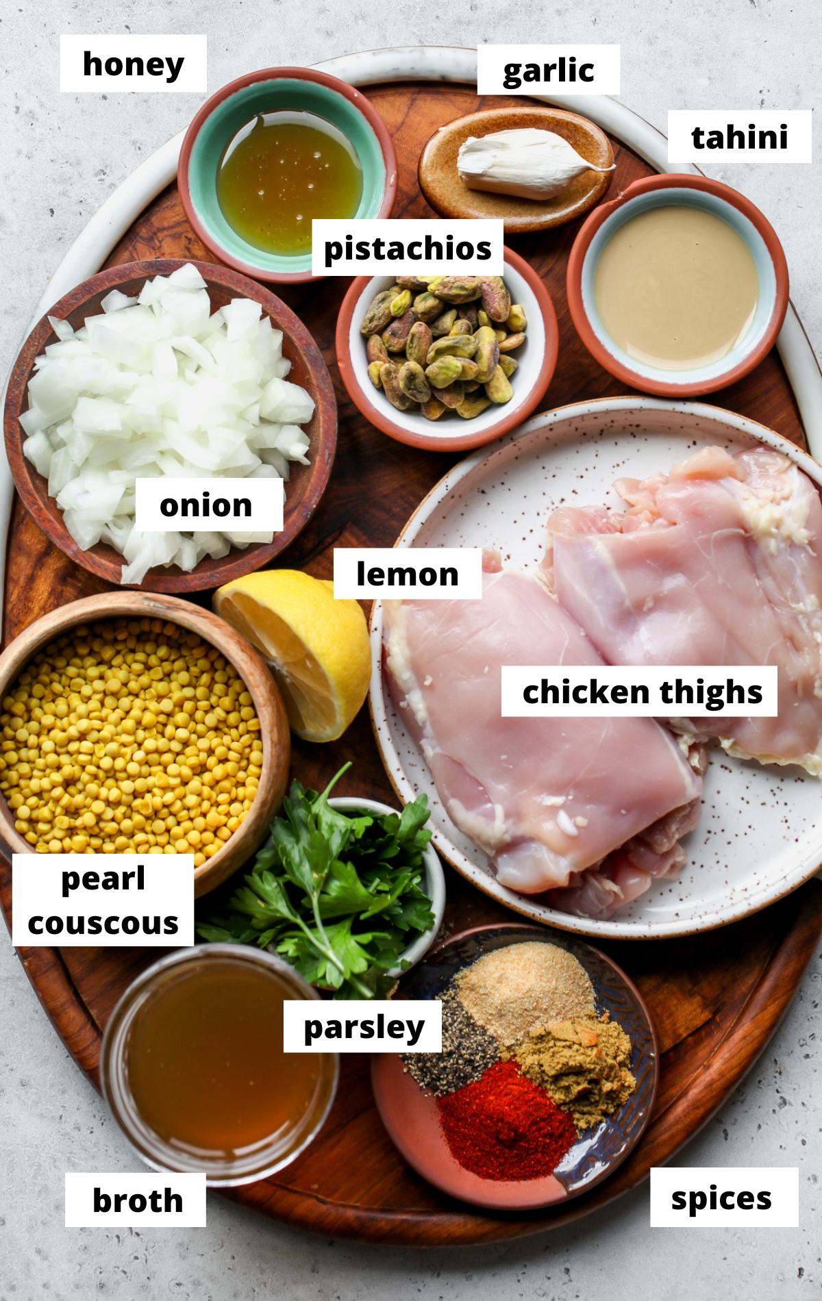 Recipe ingredients in separate bowls arranged on a wooden platter with labels.