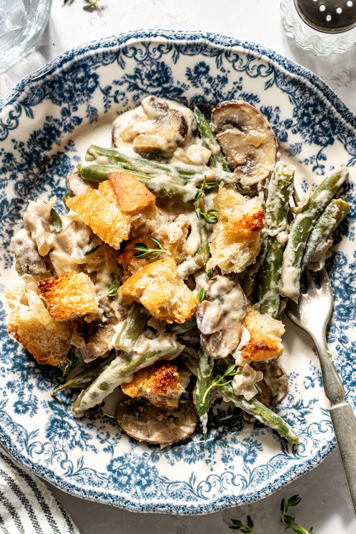 A blue and white floral plate with one serving of green bean casserole.