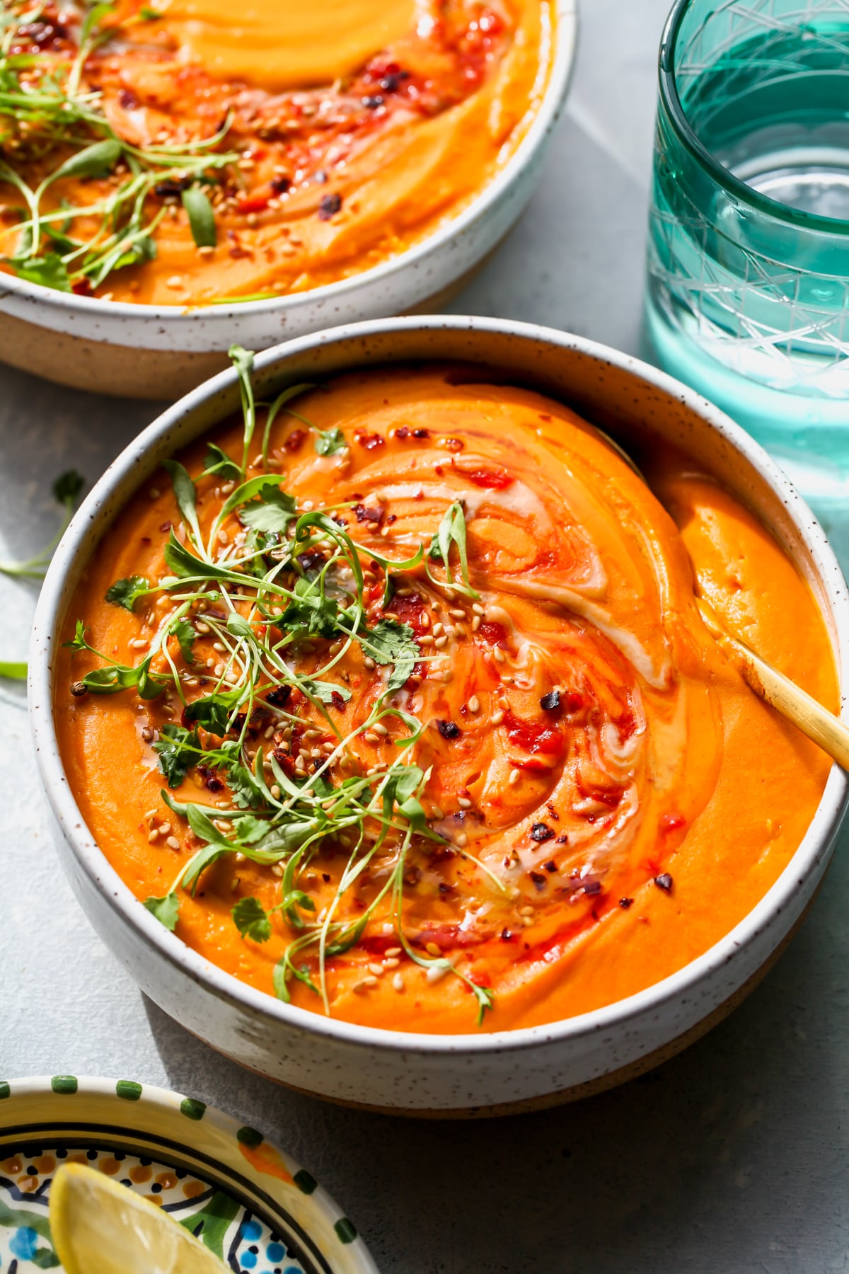 A spoon digging into a bowl of creamy carrot and lentil soup.