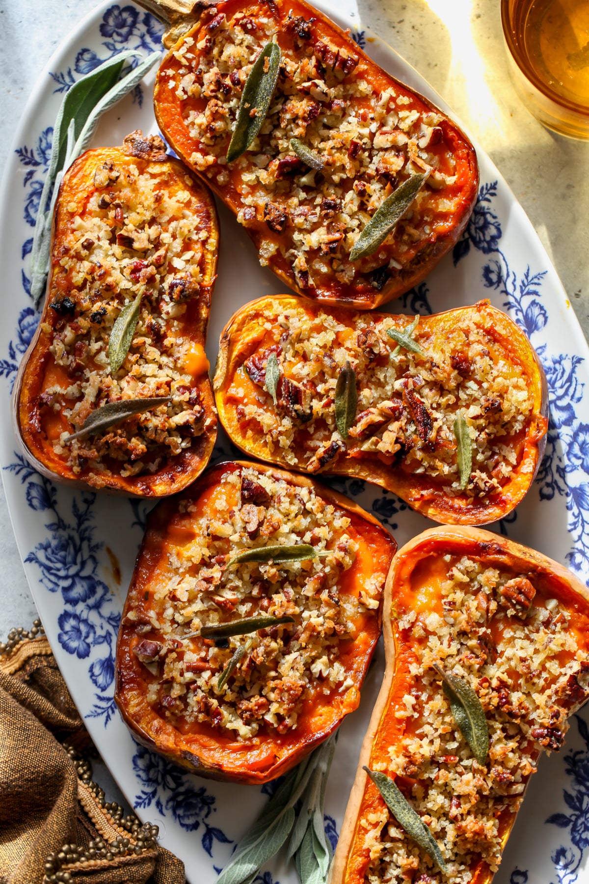 Twice-baked honeynut squash boats styled on a white and blue floral platter.