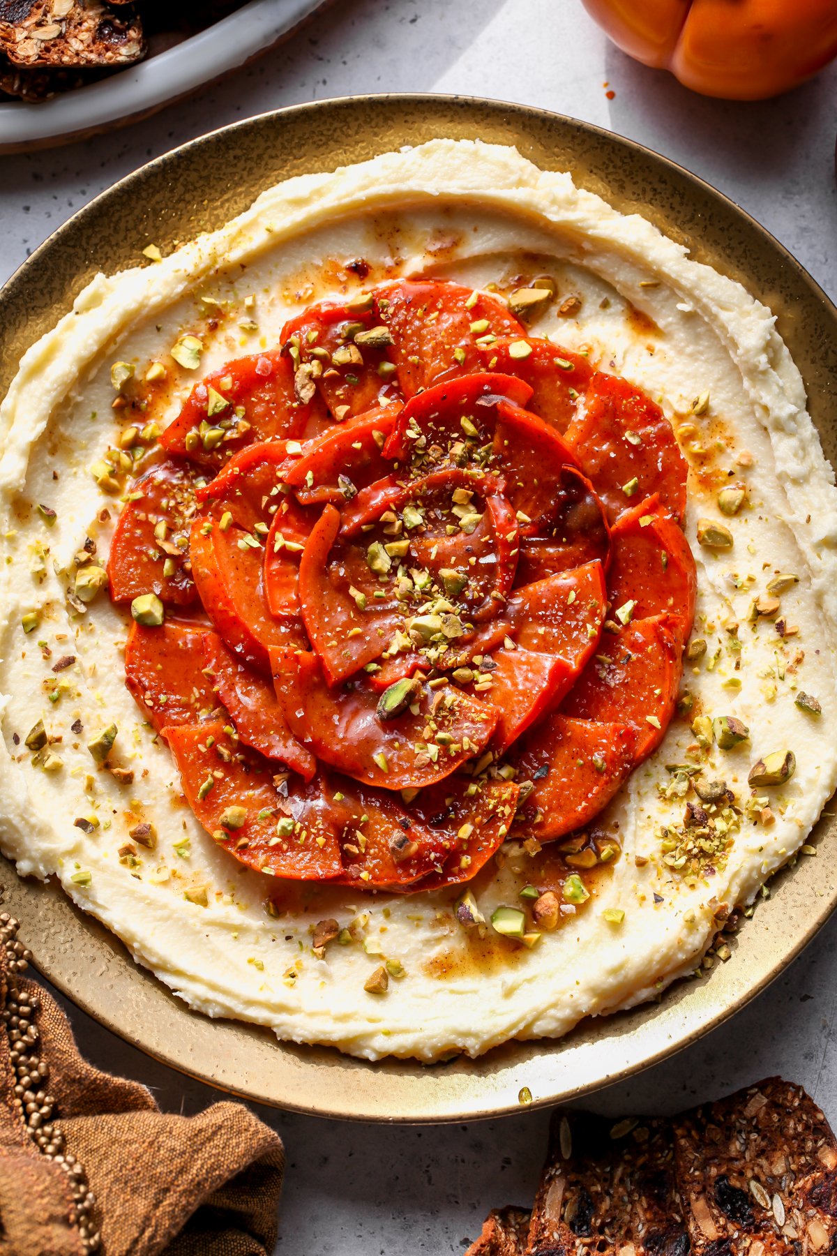 Whipped brie topped with caramelized persimmons styled on a gold platter.