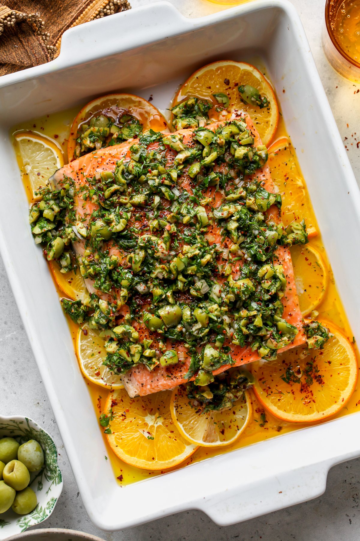 Citrus salmon roasted in a baking dish and topped with olive salsa.