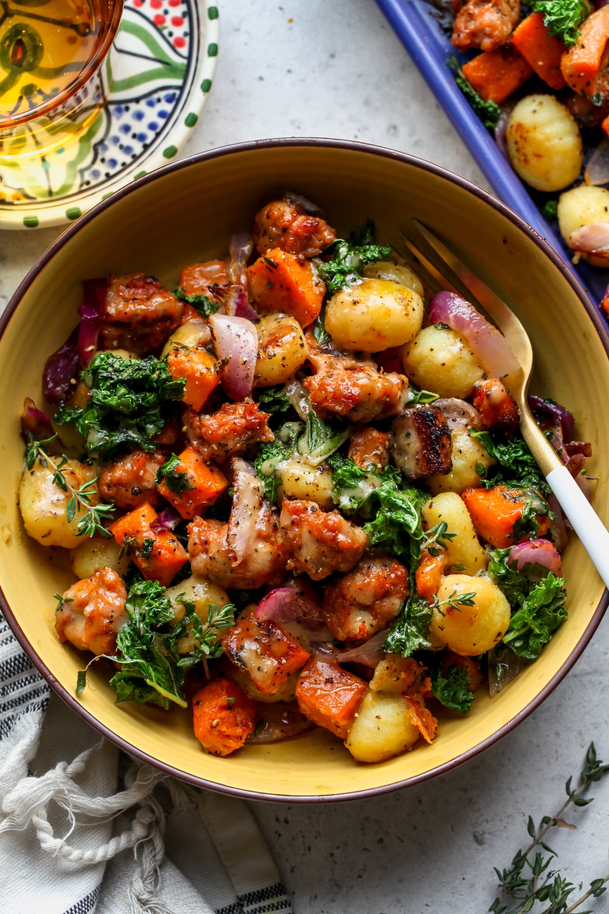 Butternut Squash and Sausage Gnocchi in a yellow bowl drizzled in sauce.