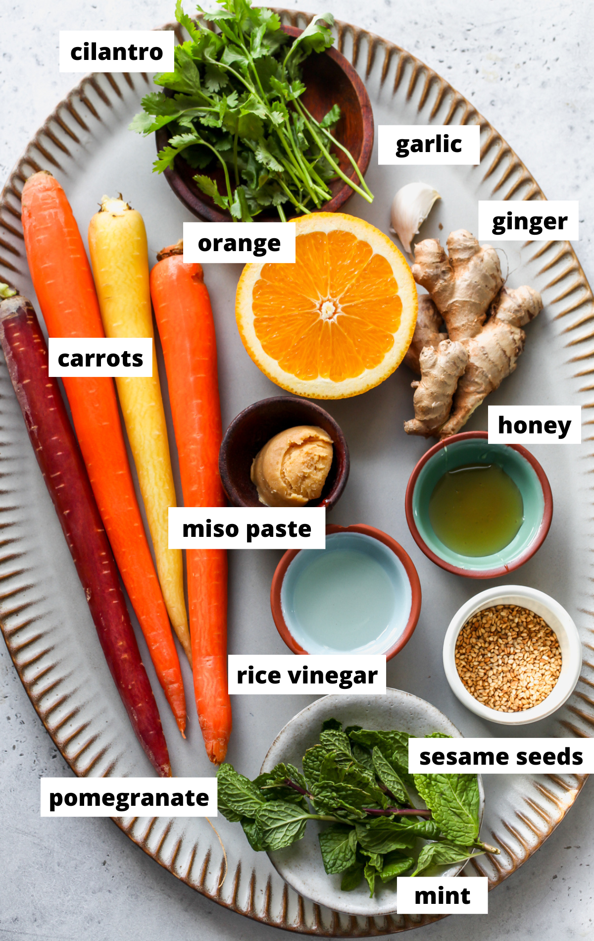Recipe ingredients in separate bowls arranged on a large blue serving platter with labels.