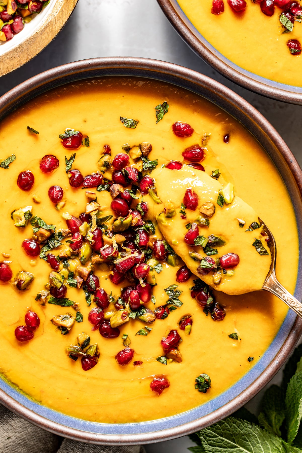 A spoon digging into a bowl of butternut coconut milk soup.
