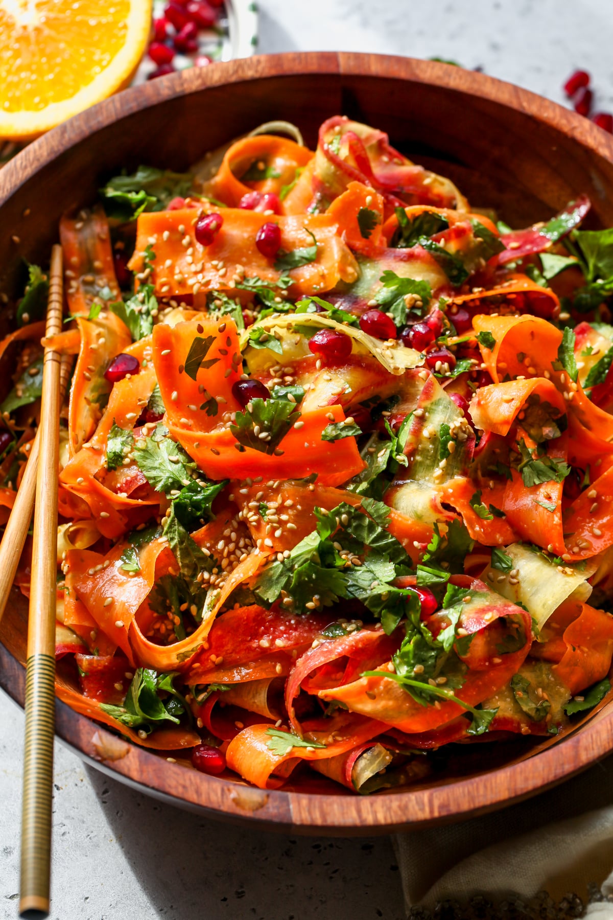 Shaved Carrot Salad with Miso-Ginger Dressing styled in a wooden serving bowl with chopsticks resting on the left side.