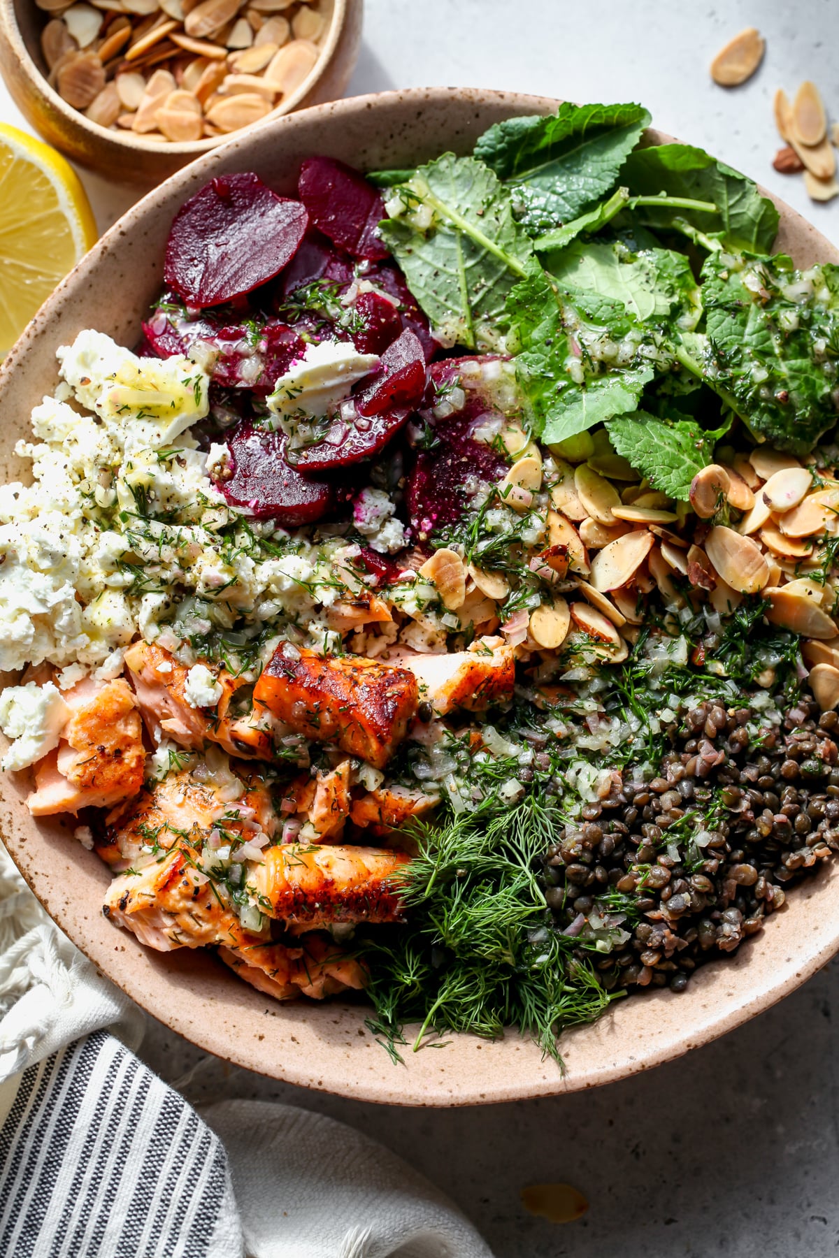 Salmon and Lentil Salad styled in a pink bowl drizzled with lemon-dill dressing.