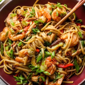 Shrimp Lo Mein being twirled with chopsticks in a large maroon bowl.