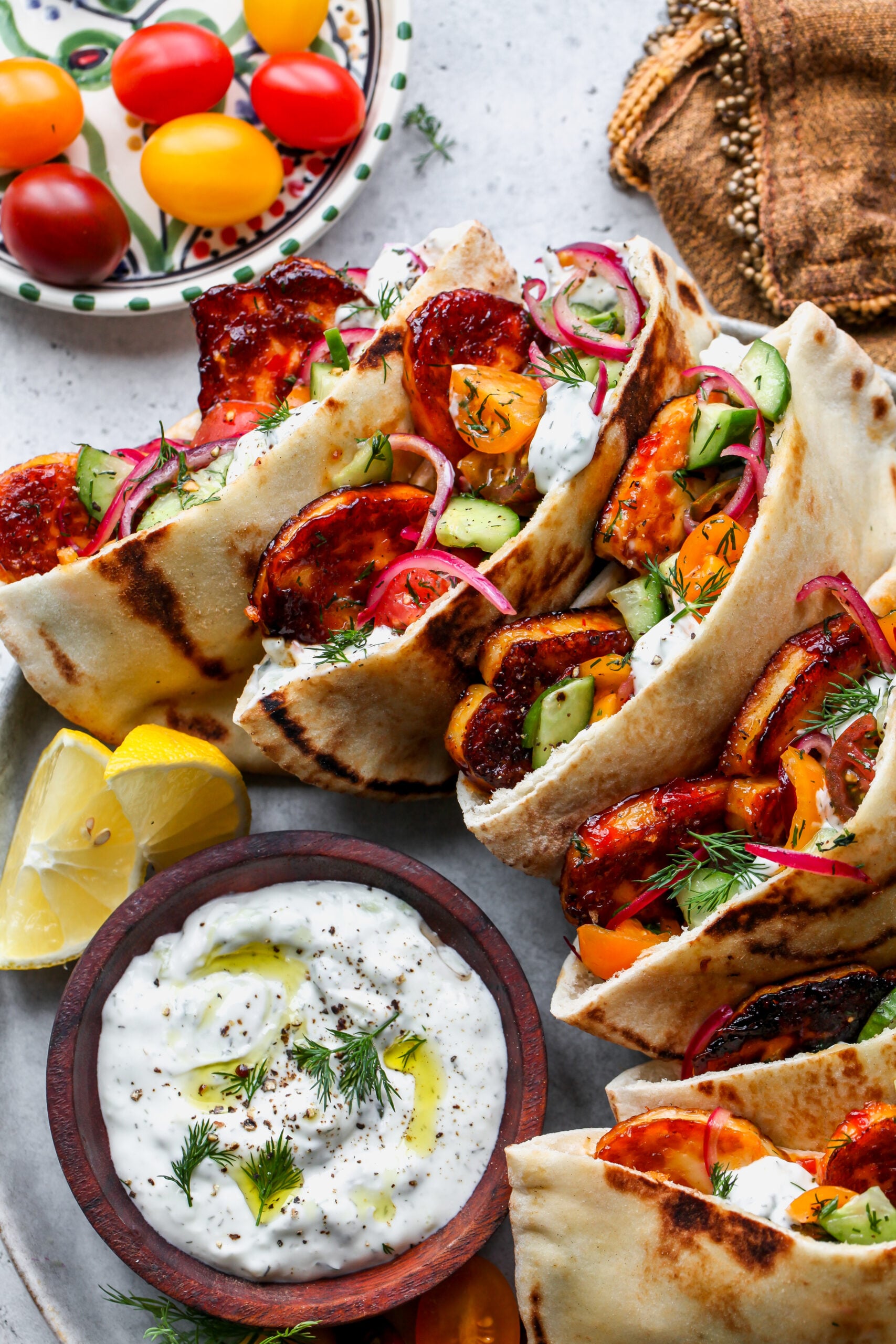 Mediterranean Halloumi Pitas arranged on a platter with a bowl of tzatziki in the center.