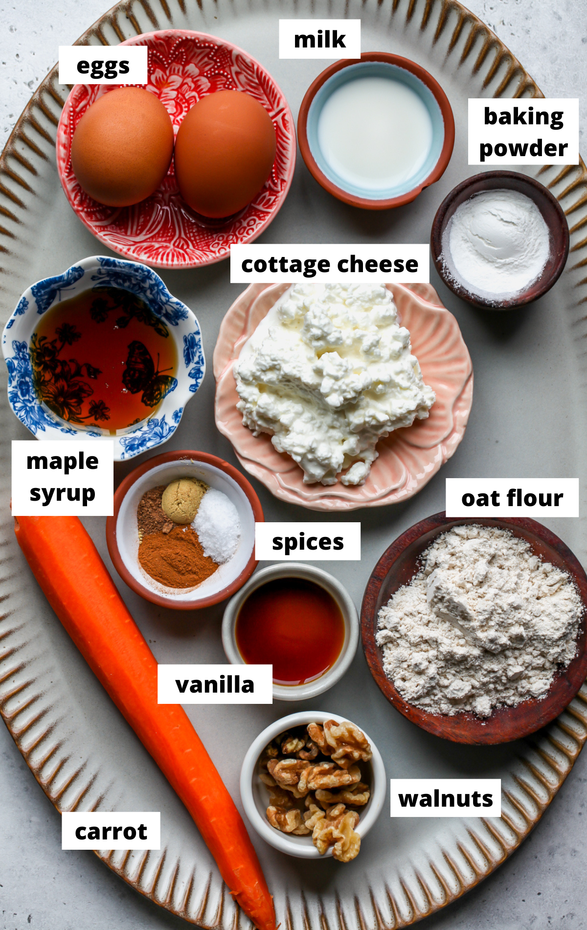 Recipe ingredients in separate bowls arranged on a large scalloped platter with labels.