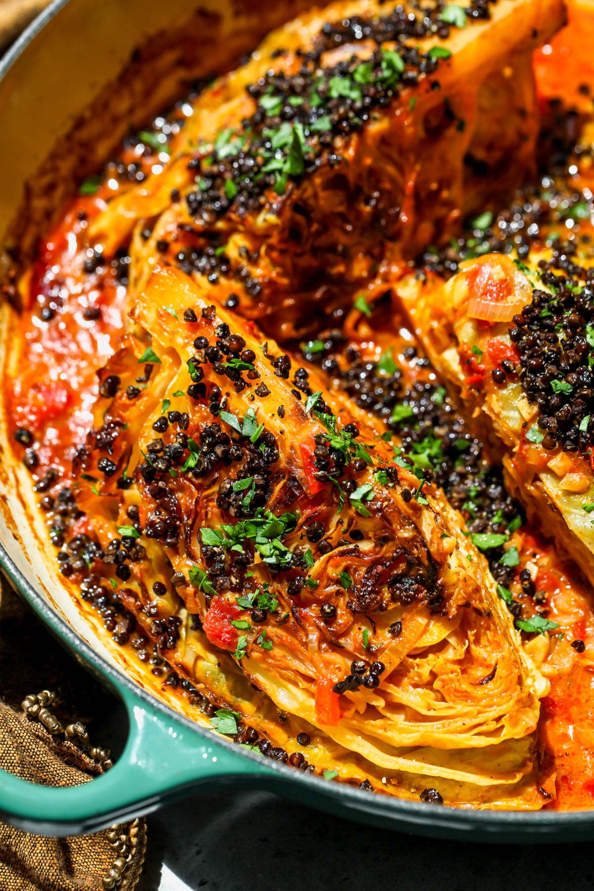 Coconut-Braised Cabbage arranged in a skillet topped with crispy lentils and fresh parsley.