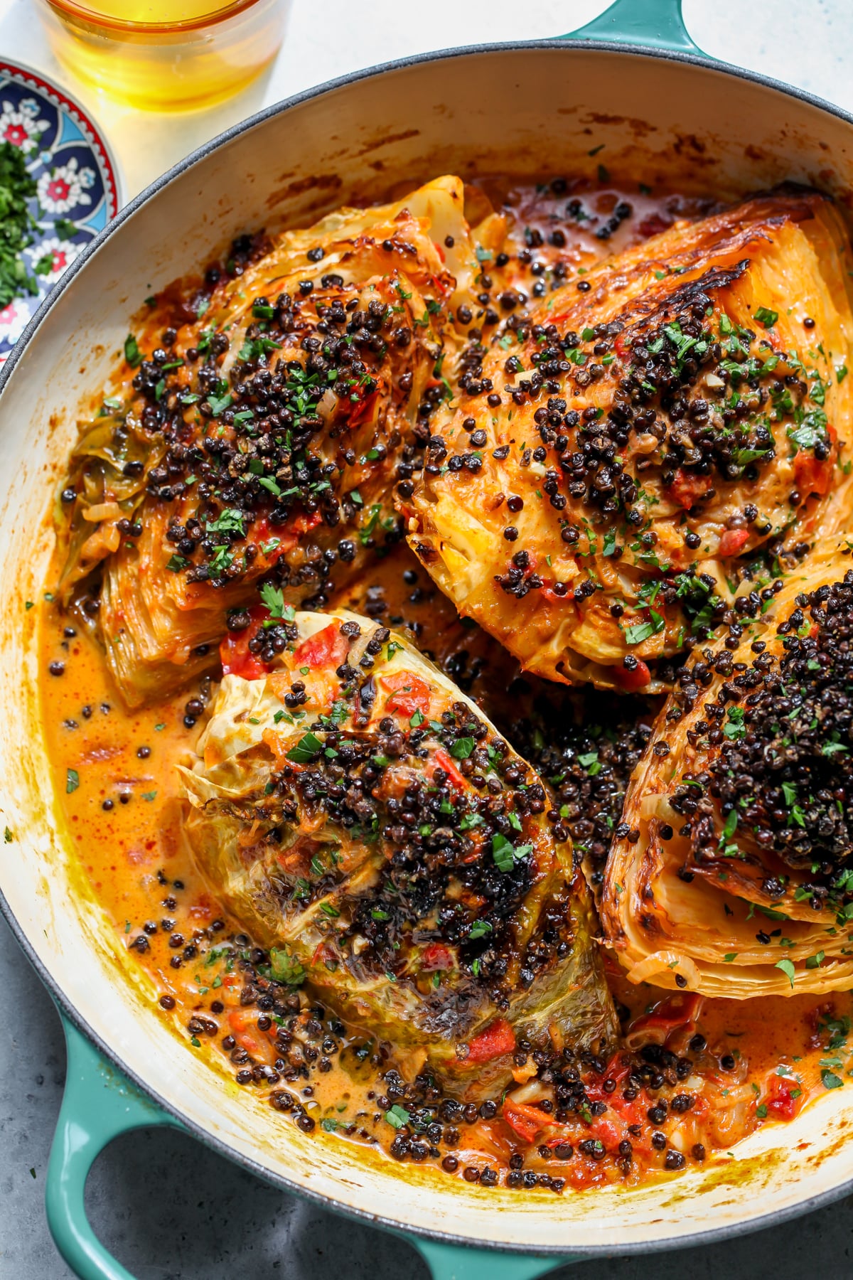 Coconut braised cabbage wedges topped with crispy lentils in a large skillet.
