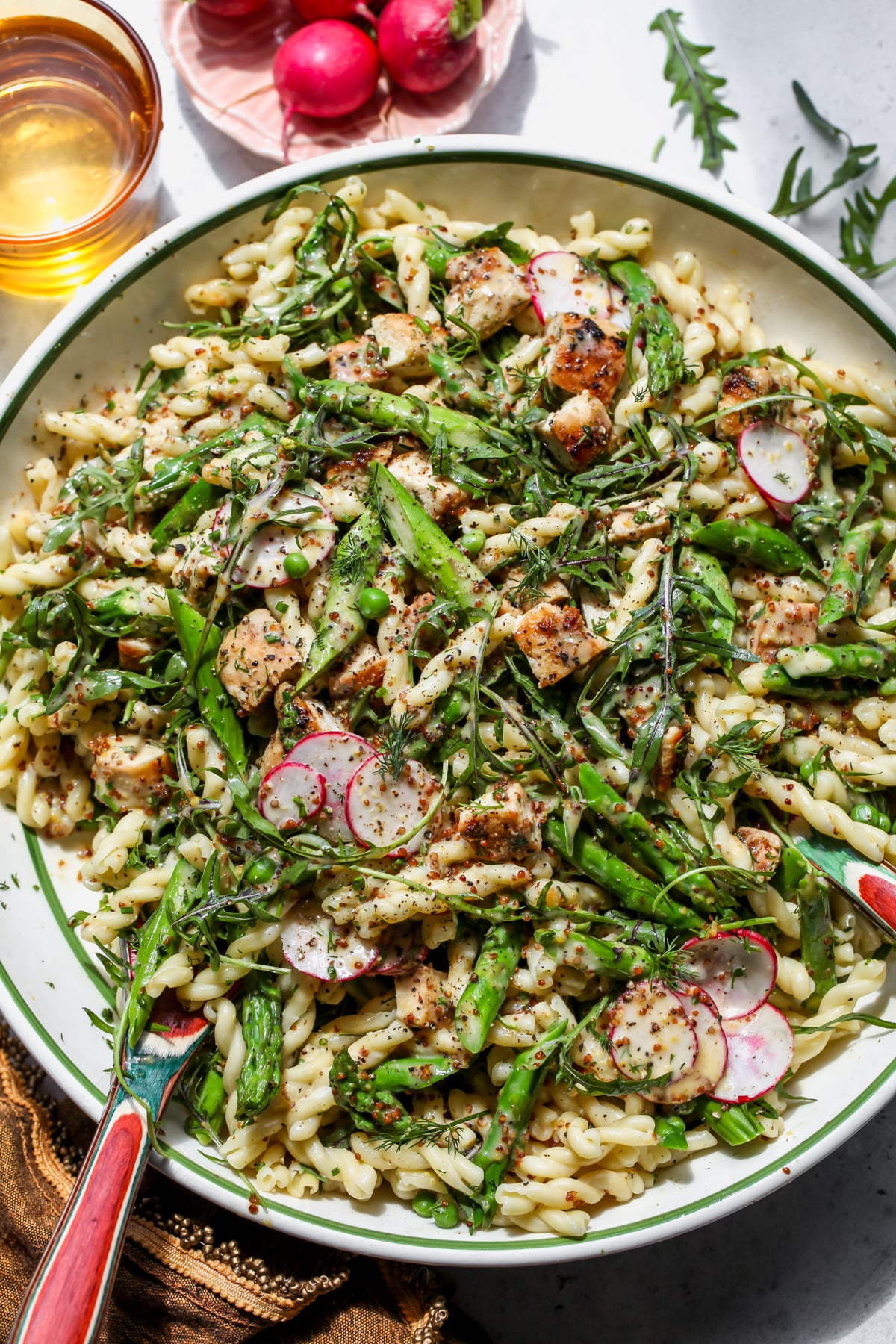 Honey Mustard Chicken Pasta Salad styled in a large mixing bowl with serving spoons resting on each side.