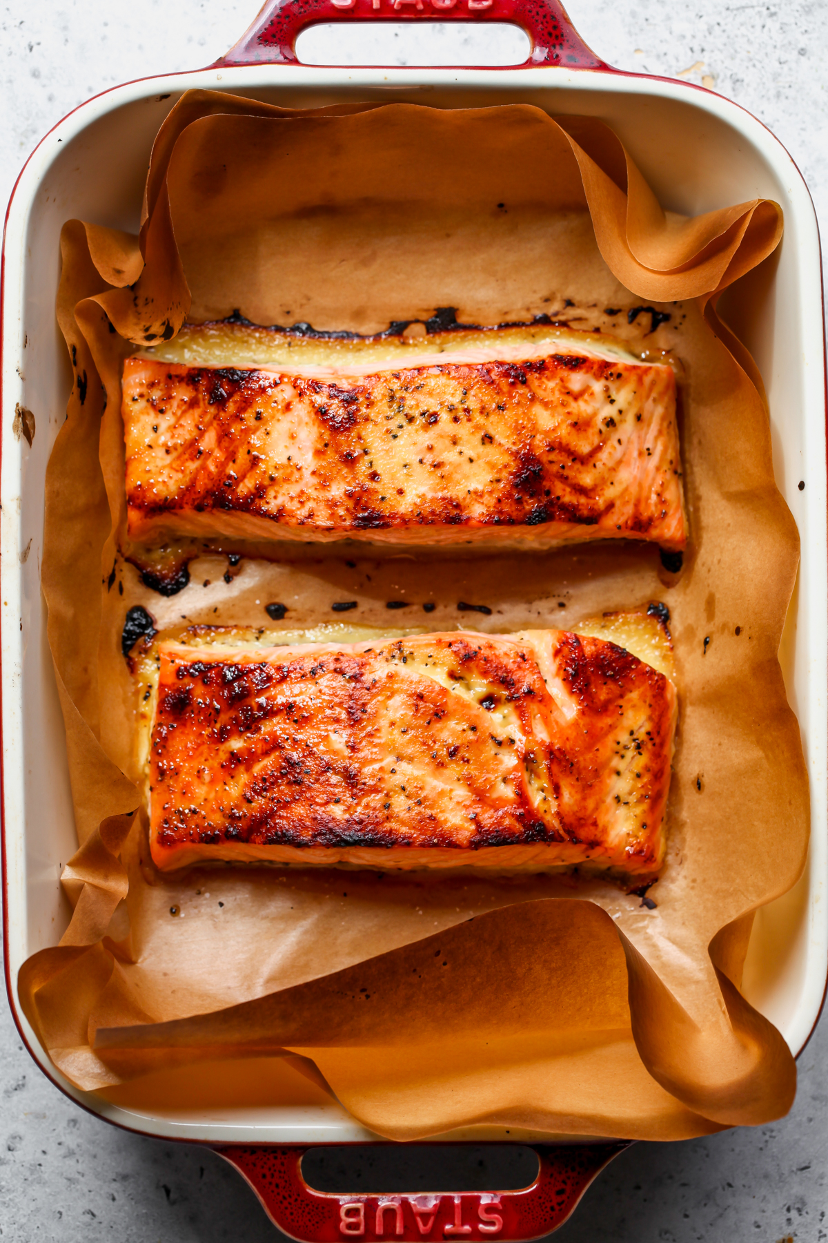 Two miso-ginger glazed salmon fillets in a baking dish after being broiled.