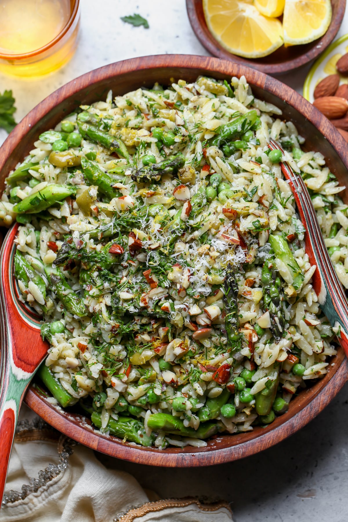 Asparagus Orzo Pasta Salad in a large wooden serving bowl on a gray surface.