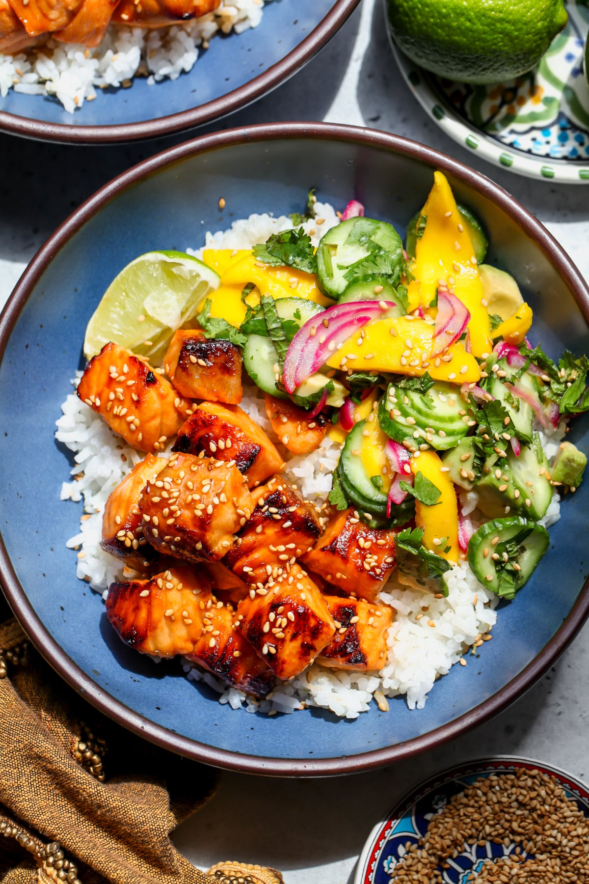 Hot Honey Salmon with Mango Salad and coconut-lime rice styled in a blue bowl.