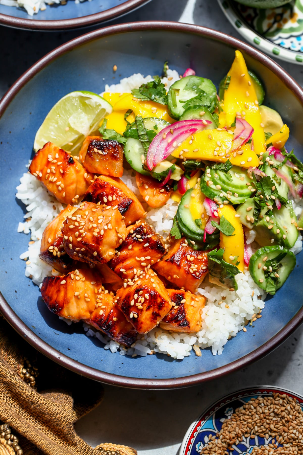 Hot Honey Salmon Bowls with Mango Salad and coconut-lime rice styled in a blue bowl.