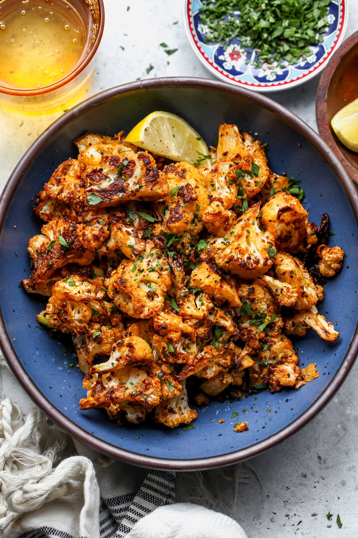 Garlic-Parmesan Roasted Cauliflower florets in a blue bowl styled on a gray surface.