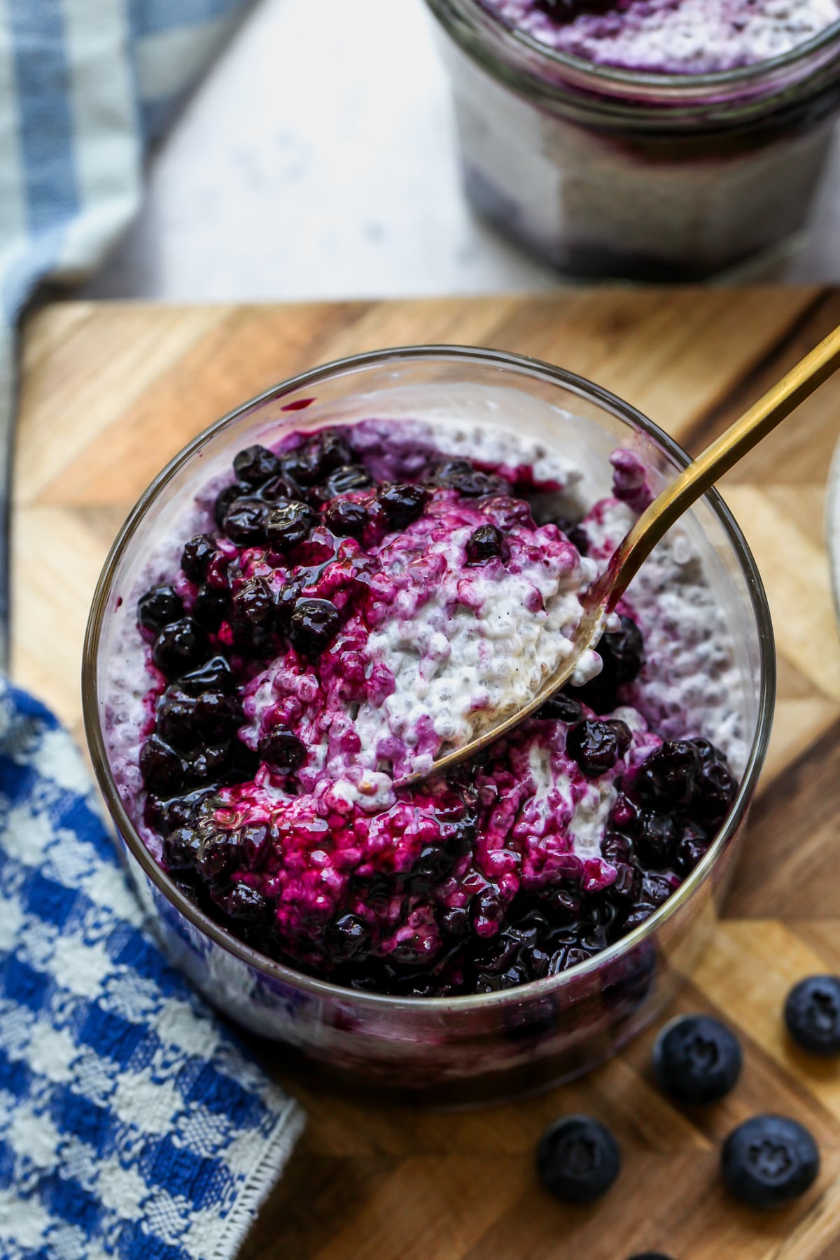 A spoon digging into a jar of chia pudding topped with wild blueberry compote.