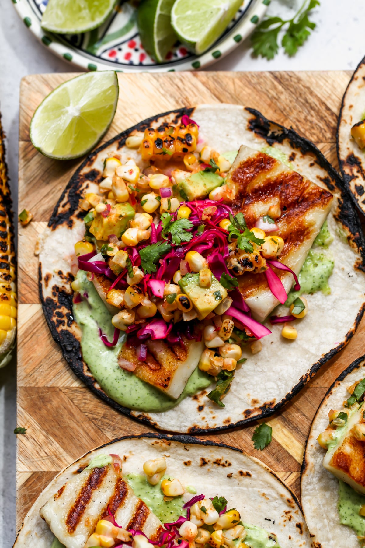 Halloumi tacos styled on a wooden cutting board with lime wedges as garnish.