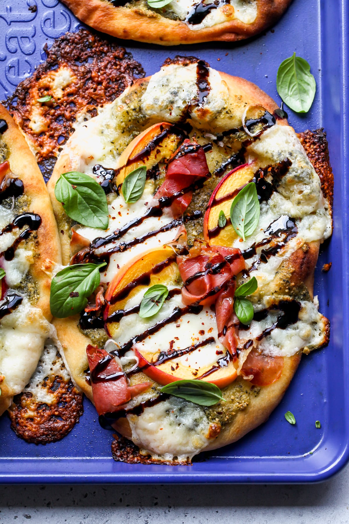 Summer Naan Pizzas after baking on a blue rimmed baking sheet.