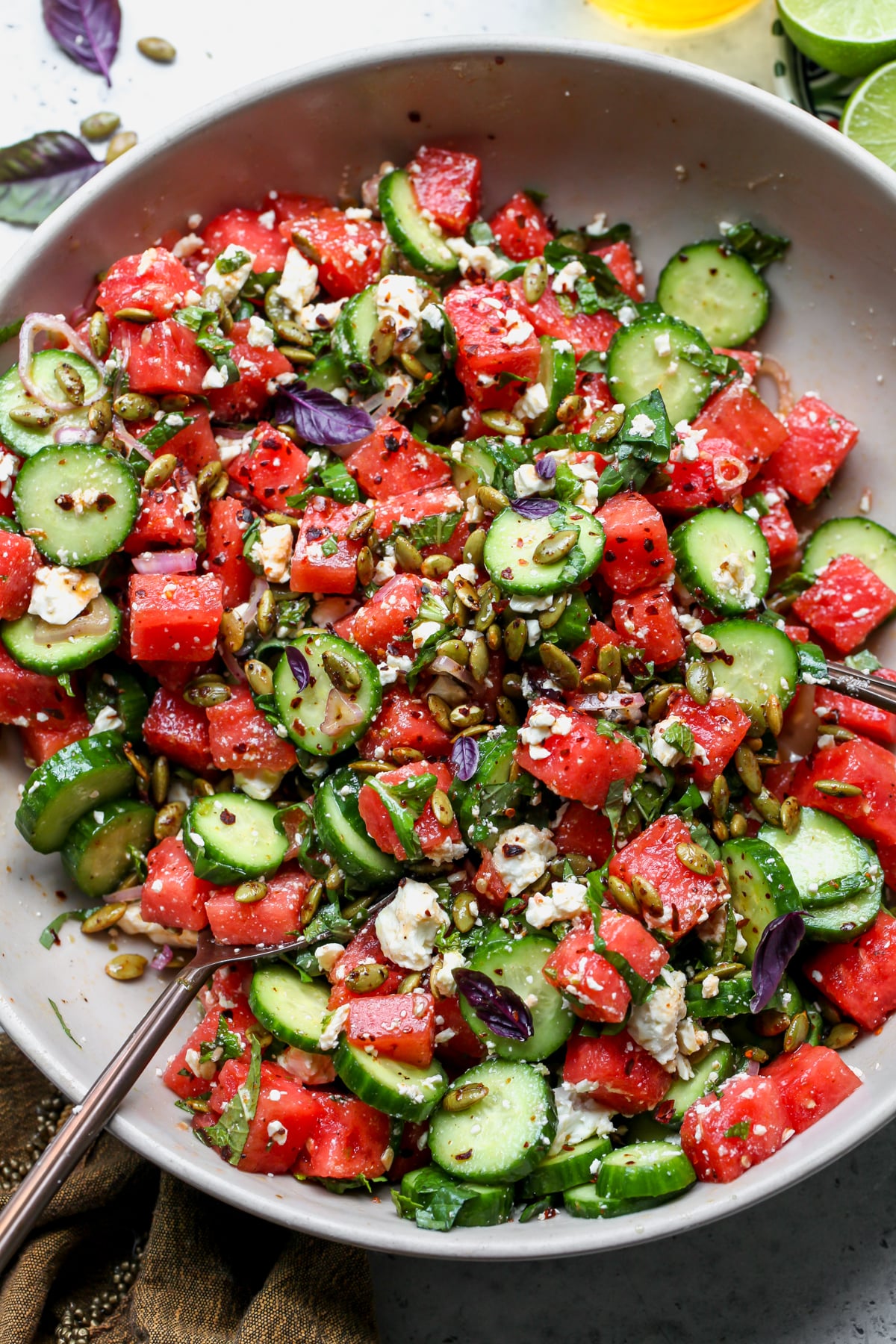 Watermelon-Cucumber Salad tossed in honey-lime dressing in a large tan serving bowl.