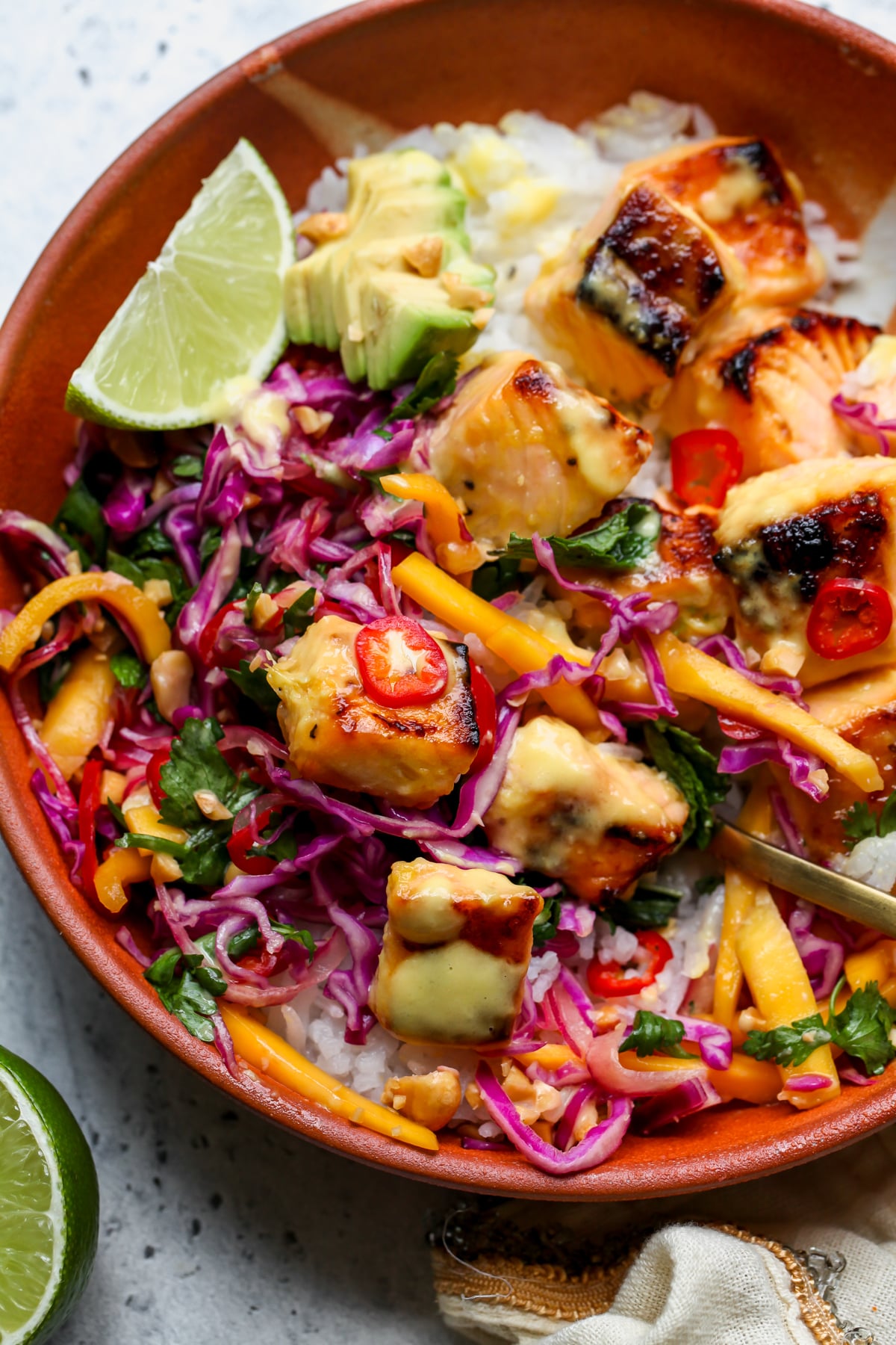 Mango-miso salmon served over rice with mango slaw in an orange bowl.