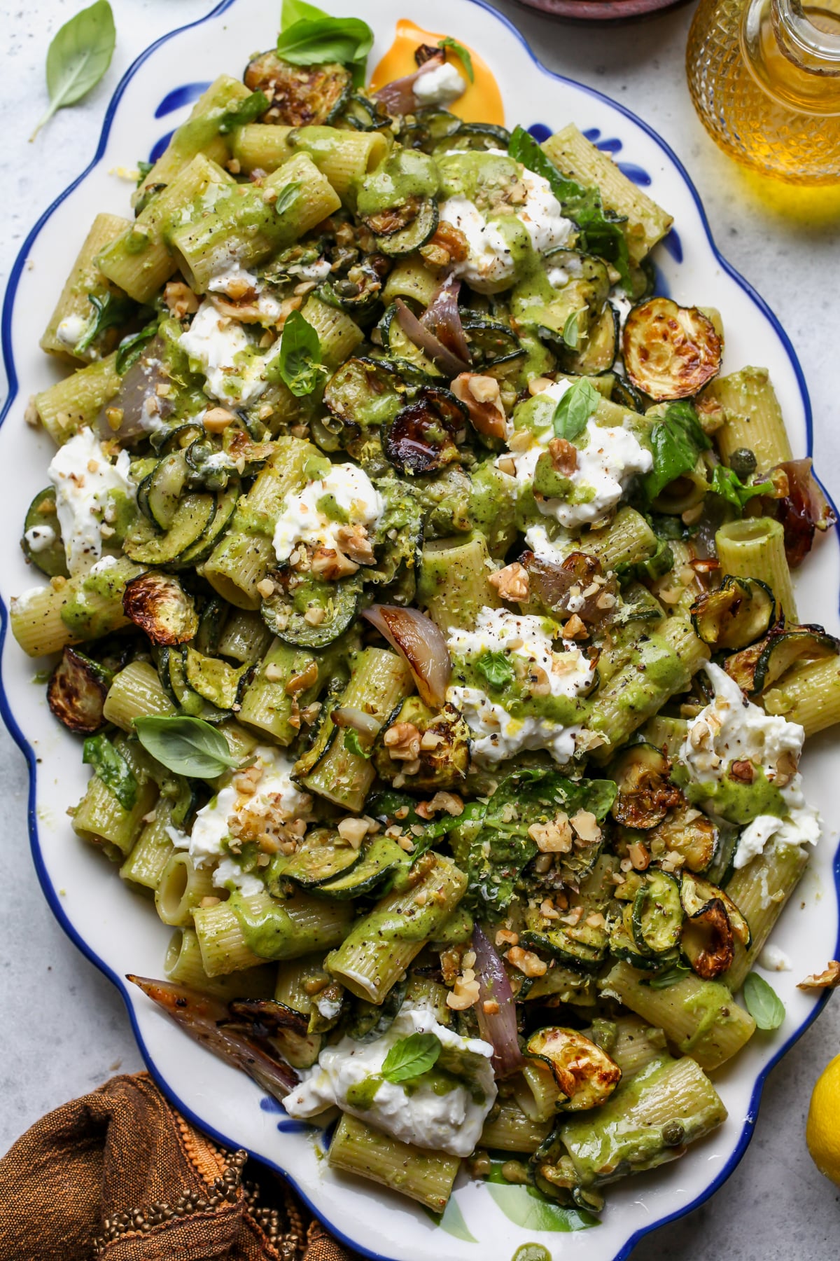 Roasted Zucchini Pasta Salad with Basil Vinaigrette styled on a scalloped white and blue platter.