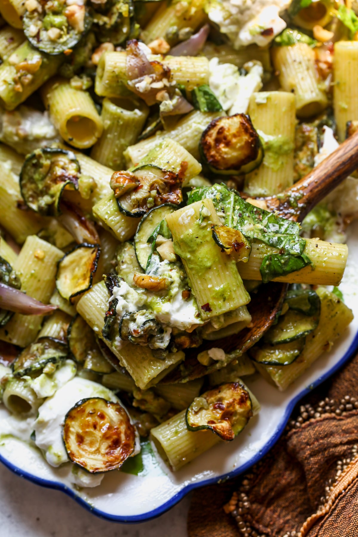 A wooden spoon scooping up a serving of pasta salad.