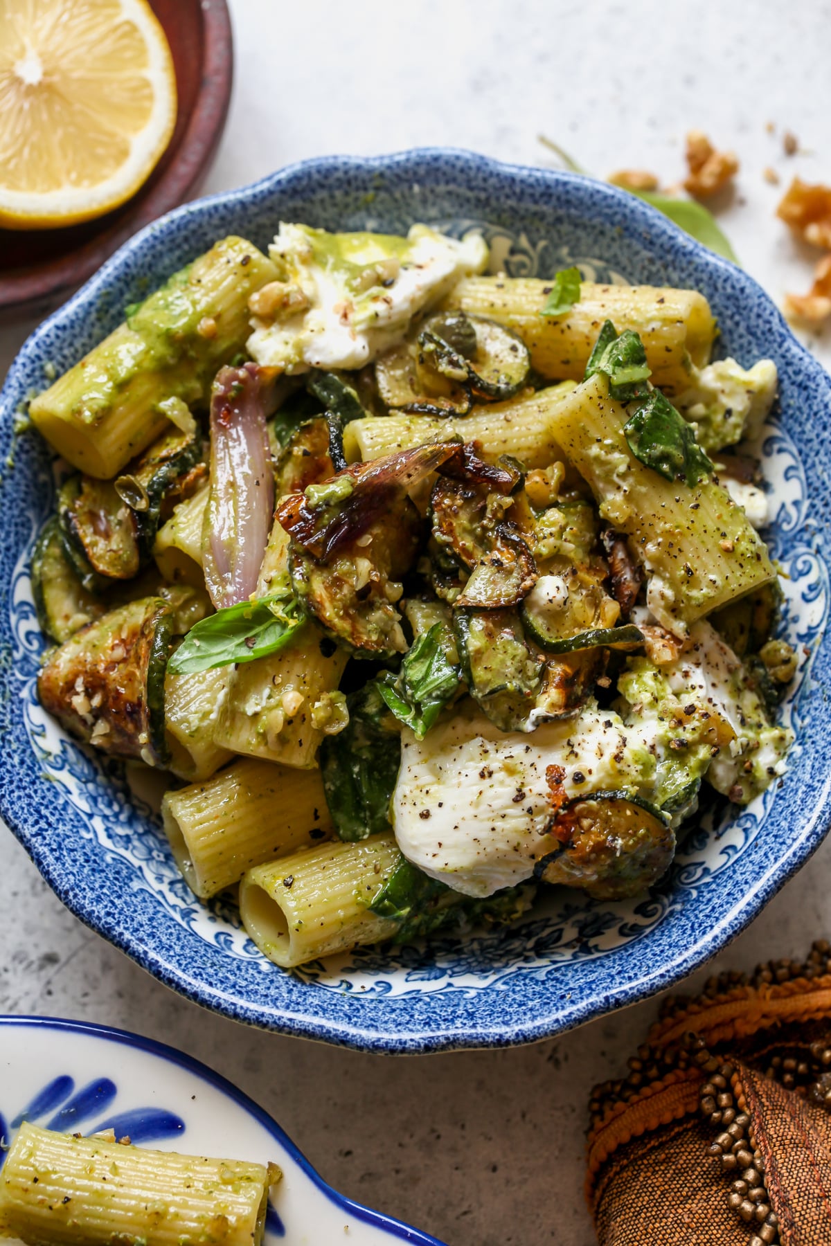 Roasted Zucchini Pasta Salad with Basil Vinaigrette styled in a small white and blue floral bowl with dollops of burrata cheese.