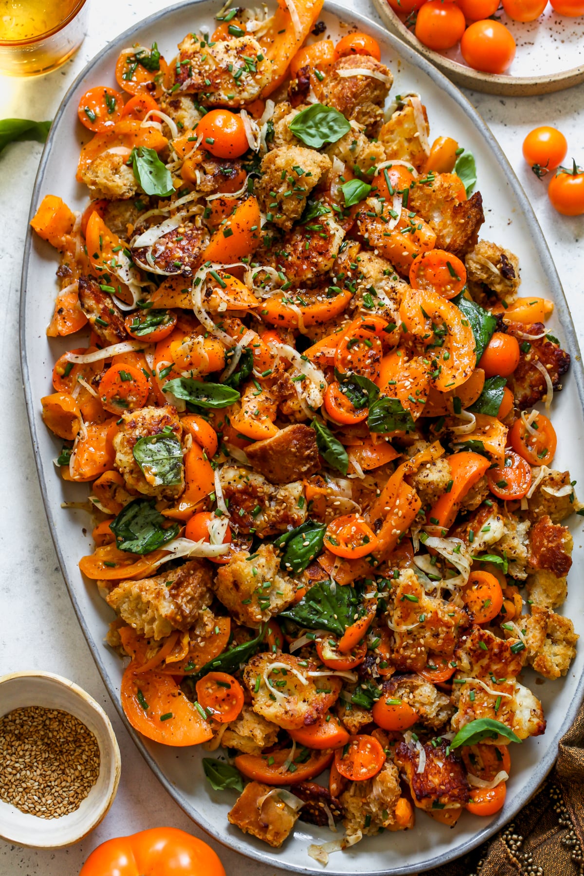 Sungold Tomato Panzanella with Halloumi and sourdough bread styled on a large white oval platter.